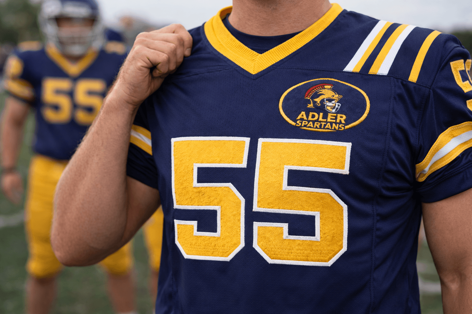 Navy blue Adler Spartans football jersey with yellow number 55 and Spartan helmet logo.